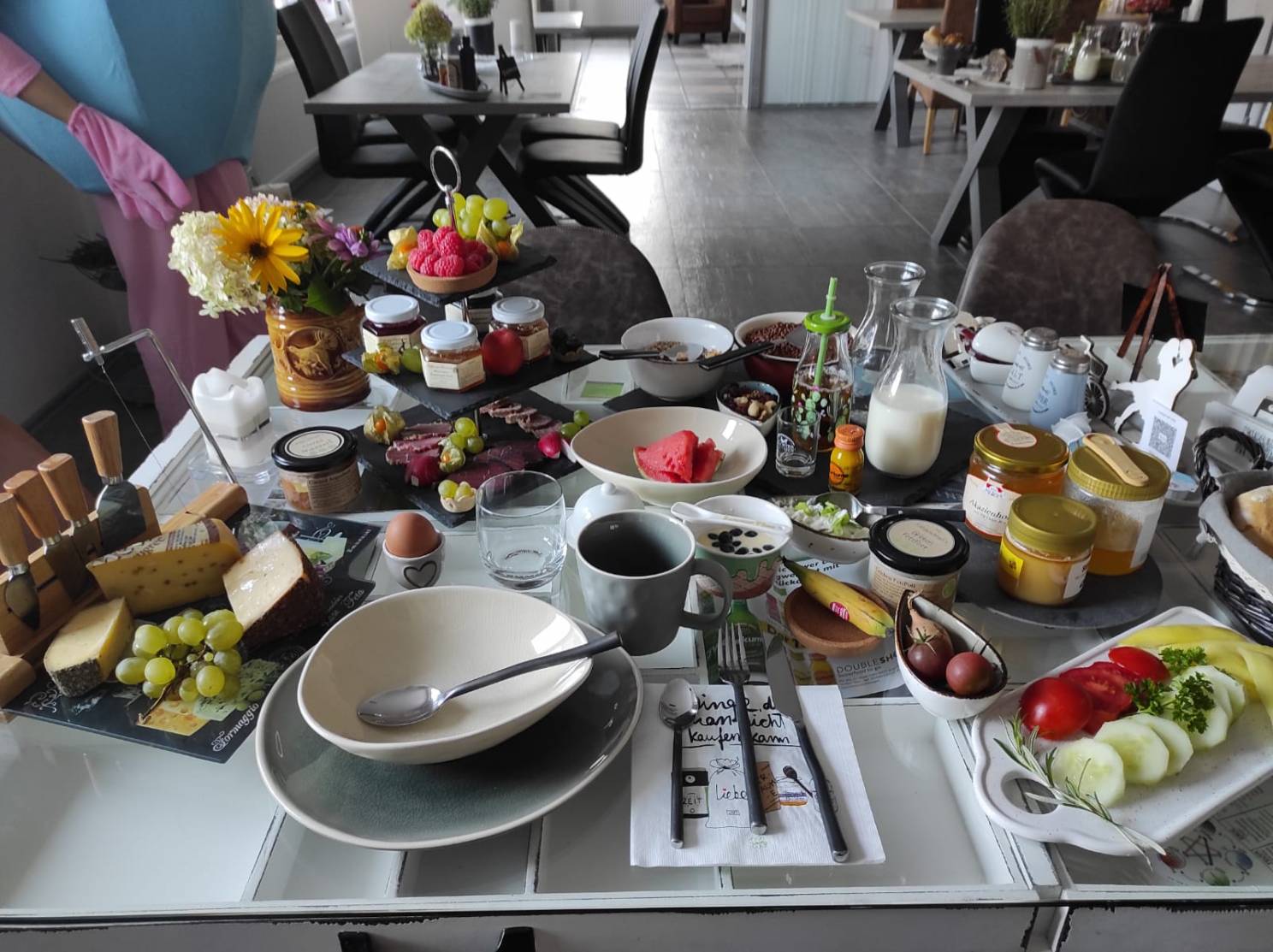 reichlich gefüllter Frühstückstisch im Hotel La Maison Bett & Bike zur Übernachtung mit Obstteller, Gemüseteller, Käseplatte, Honigplatte, Marmelade, Eiern und Milch in der Prignitz (Brandenburg)