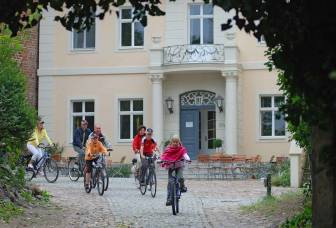 Vorschaubild Radfahrer fahren über Kopfsteinpflaster vor der historischen Burg Lenzen, in der sich heute ein Hotel und Restaurant befinden