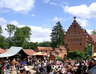 Vorschaubild viele Menschen an Markständen auf dem Mittelalterlichen Spektakel auf der Plattenburg im Sommer unter blauem Himmel