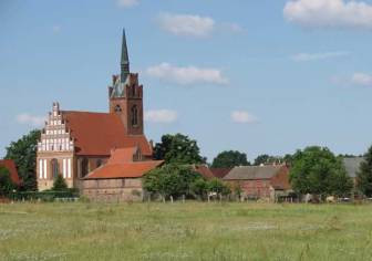 Vorschaubild Wallfahrtskirche im Dorf Alt Krüssow vor einer blühenden Wiese im Sommer unter blauem Himmel