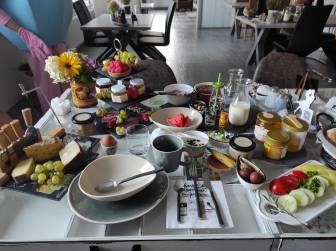 Vorschaubild reichlich gefüllter Frühstückstisch im Hotel La Maison Bett & Bike zur Übernachtung mit Obstteller, Gemüseteller, Käseplatte, Honigplatte, Marmelade, Eiern und Milch in der Prignitz (Brandenburg)