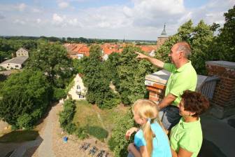 Vorschaubild Großeltern und Enkelin blicken vom Turm der Burg Lenzen auf die historische Altstadt von Lenzen mit Fachwerkhäusern und der St. Katharinen Kirche
