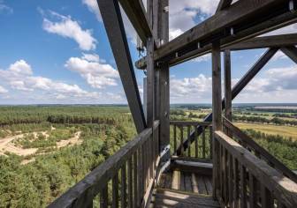 Vorschaubild Blick vom größten hölzernen Aussichtsturm Deutschlands im Blumenthal am Wanderweg Nonnenpfad mit Aussicht auf die Weite Prignitzer Landschaft mit Feldern und Nadelwald sowie einen blauen Frühlingshimmel