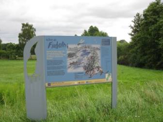 Vorschaubild Informationstafel auf einer Wiese mit Gräsern und sattgrünem Gras mit dem Titel "Im Reich des Fischotters"