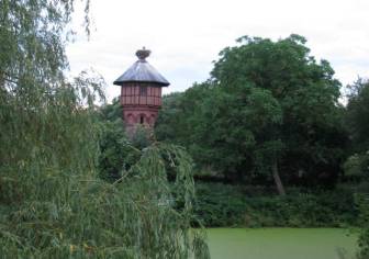 Vorschaubild Weide und Teich mit Schwebealgen (Entengrütze) vor dem Wahrzeichen des Europäischen Storchendorfes Rühstädt, dem Wasserturm mit einem Horst, in dem ein Storch steht