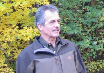 Vorschaubild zertifizierter Natur- und Landschaftsführer Jürgen Strache vor einem Busch in Funktionskleidung, grauhaariger Mann mit Bart