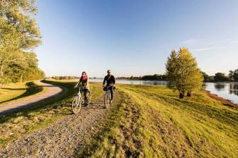 Vorschaubild Paar lächelnder Radfahrer auf dem Elbdeich mit Blick in die Elbalaue auf dem Elberad inmitten des Biosphärenreservates Flusslandschaft Elbe Brandenburg in der Herbstsonne