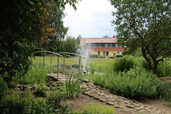 Vorschaubild Zum Tag der Offenen Gärten öffnet der Martinshof mit Feldsteinweg und Brücke über einem Teich mit Bepflanzung